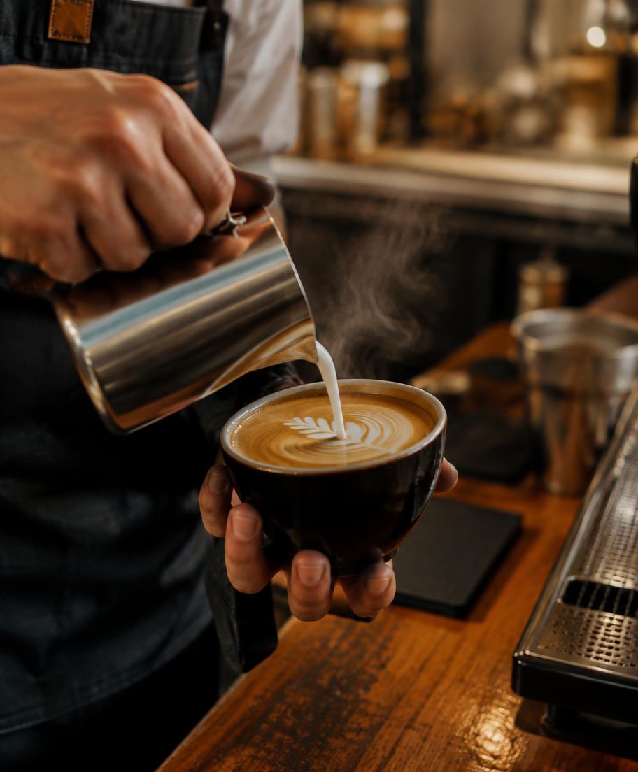 A barista pouring milk into a fresh espresso